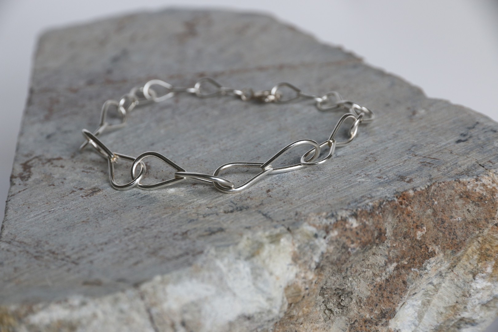 Handmade silver bracelet displayed on stone
